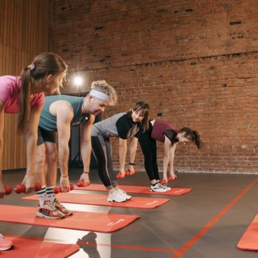Fitness group performing exercises with dumbbells in a modern yoga studio setting.